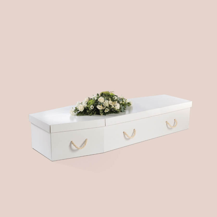 White coffin with floral arrangement on a beige background